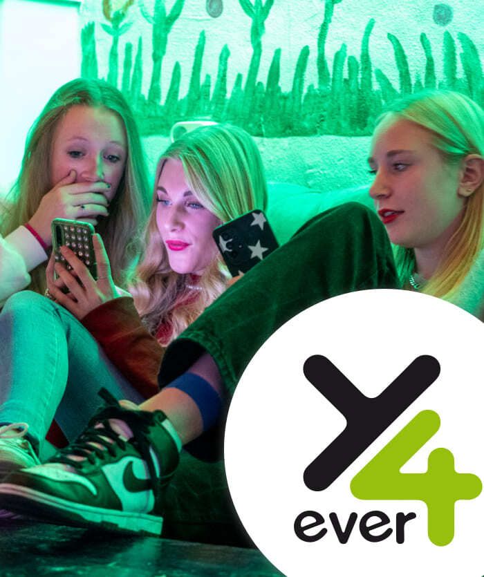 Drie tienermeisjes zitten samen, kijkend naar smartphones, met een groen getinte muur en een Y4ever-logo op de voorgrond: de perfecte inspiratie voor webshops of online diensten gericht op Generatie Z.