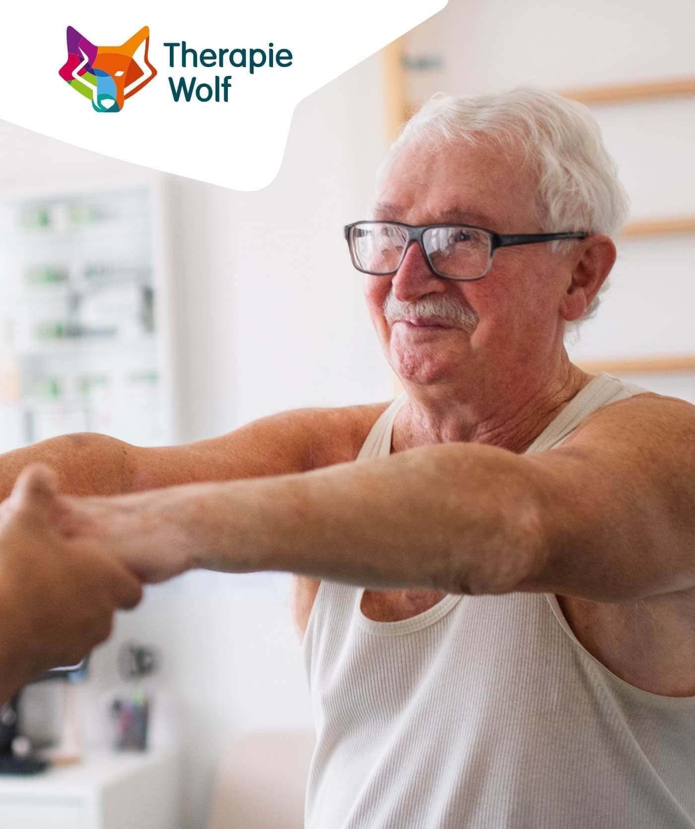 Een oudere man in een wit tanktopje doet armoefeningen met assistentie in een therapieomgeving. Het logo van Therapie Wolf en verwijzingen naar online diensten zijn linksboven zichtbaar.